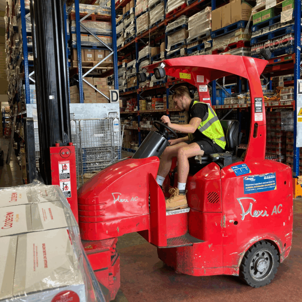 warehouse driver on red forklift wearing a high vis jacket moving palettes in foodservice industry