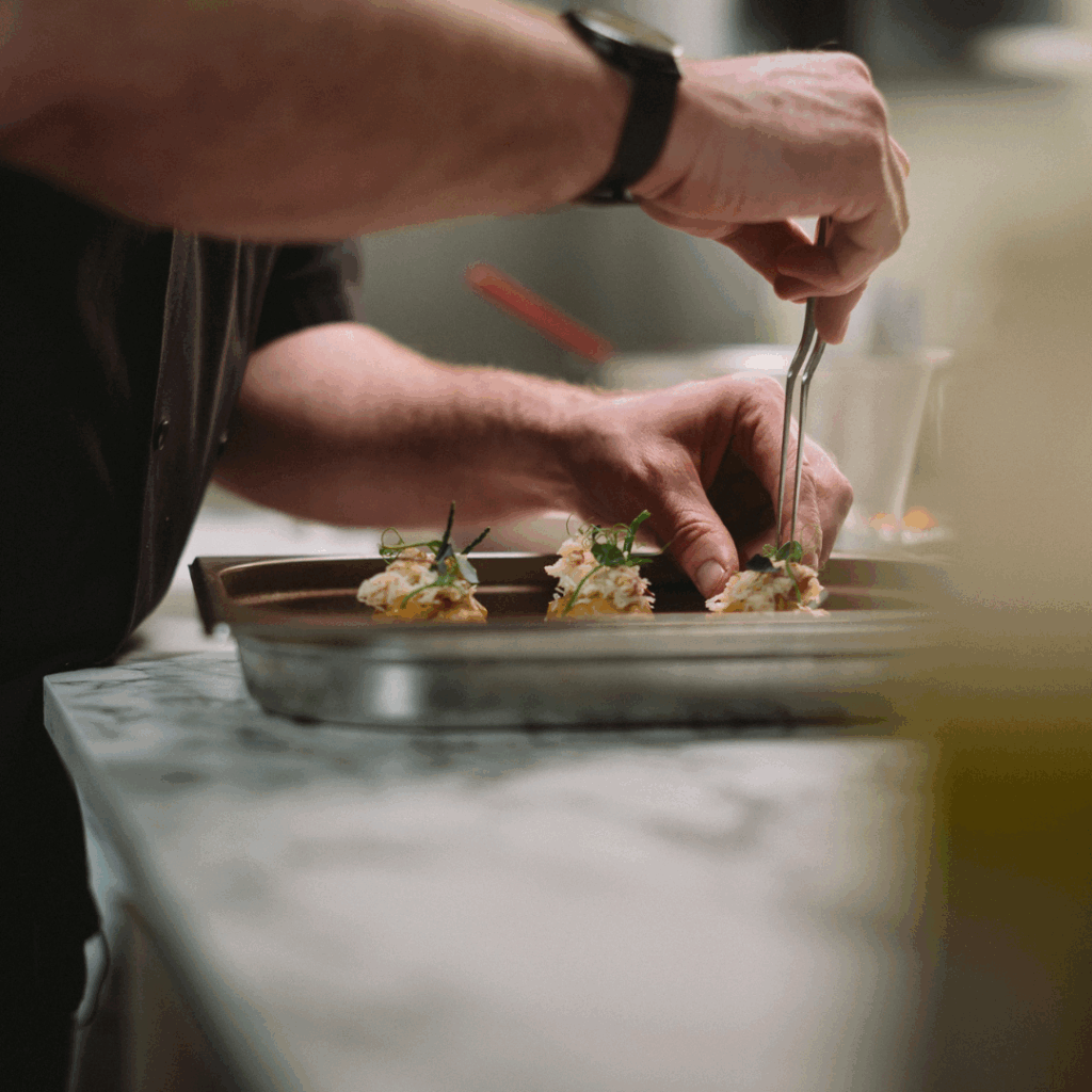 Oxford Guild of Chefs Image, Ben Gibbons plating up food.